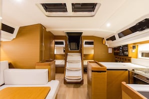 Un intérieur compact et bien éclairé, comprenant un espace de couchage central, une kitchenette et un petit meuble pour les divertissements.
