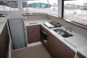Cozinha compacta com pia, fogão e armários, com vista para um porto cheio de barcos.