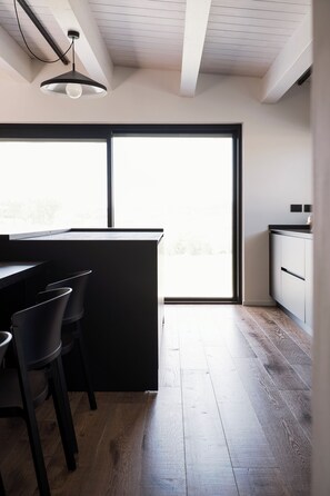 A modern kitchen with a large window, wooden flooring, and a minimalist design. - Maison Lagerstroemie -Exclusive Villa with Private Pool in Le Marche, Filottrano (Filottrano)