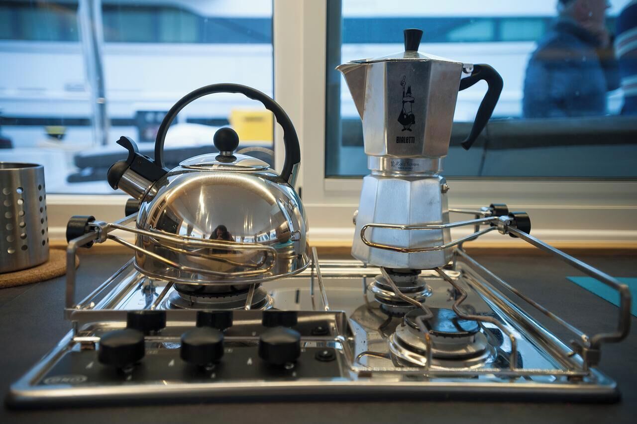 Une cuisine avec une bouilloire et une machine à café sur la cuisinière.
