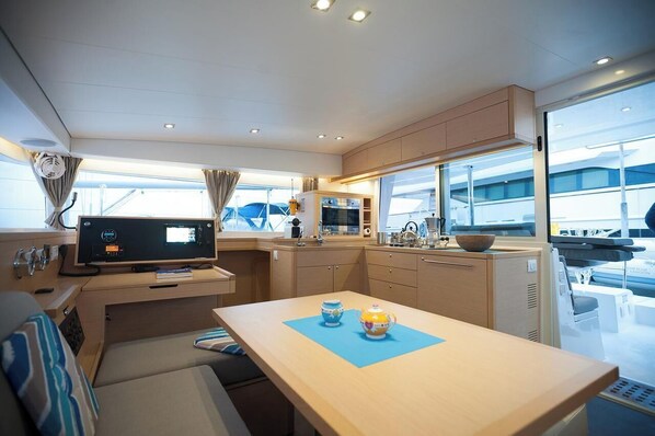 A compact kitchen with a TV, a dining table with two teapots, and a window overlooking the deck.