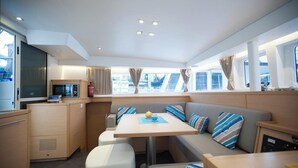 A compact galley with a microwave, stove, and small refrigerator. There is a seating area with a table and cushioned benches. - Sun-Kissed Sailing: A Luxurious Beach Experience in Nikiti, Macedonia (Nikiti)