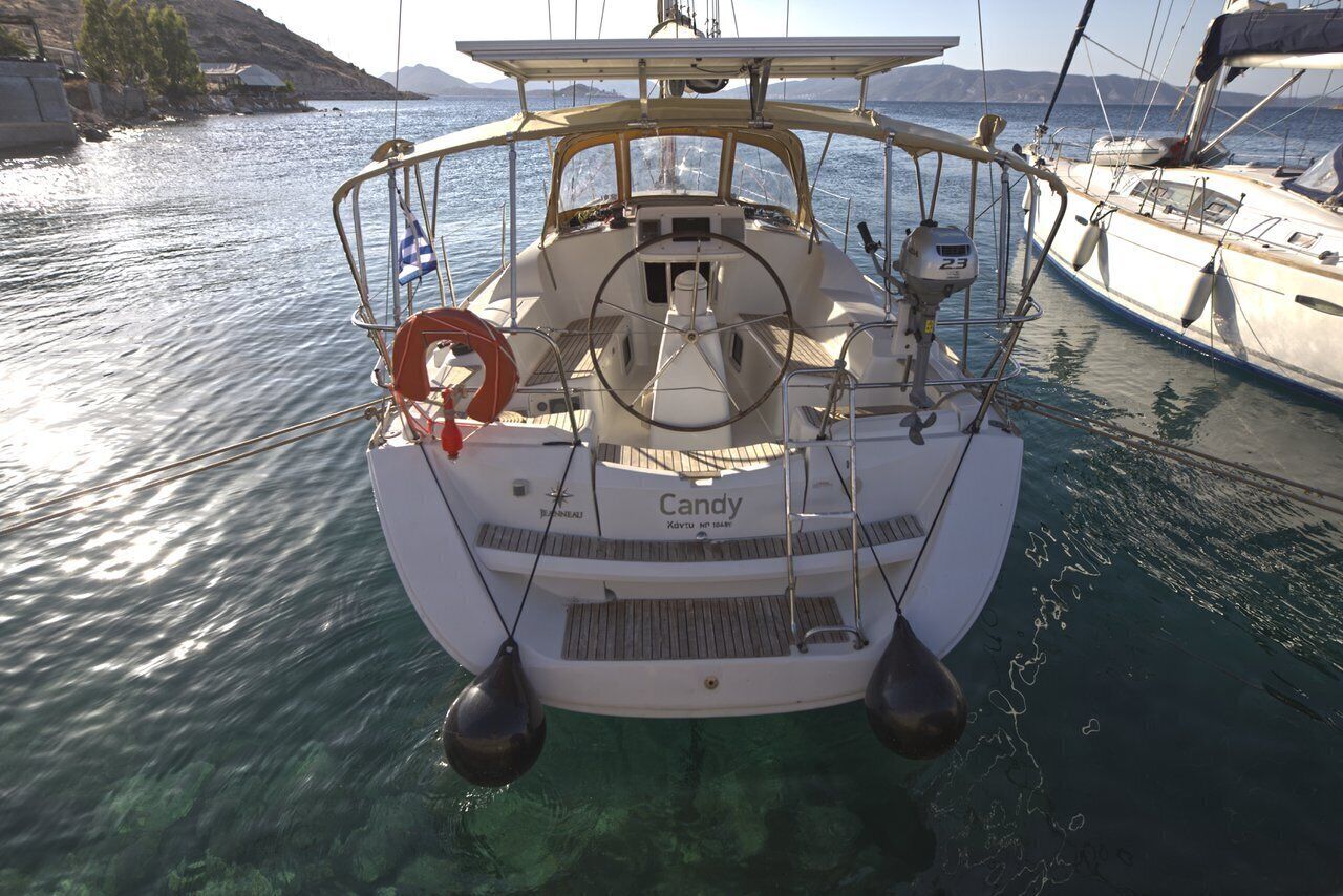 A boat named 'Candy' docked at a marina with clear water, a lifebuoy, and a steering wheel.