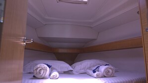Una cabina con due letti, ognuno con asciugamani arrotolati e cuscini.