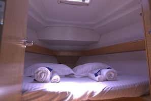 Une cabine équipée de deux lits, chacun ayant des serviettes et des oreillers pliés à disposition.