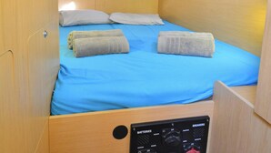 En kompakt hytte med køjeseng, kontrolpanel og en lille reol med bøger.