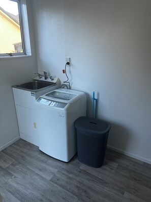 A laundry room with a washing machine, a sink, and a trash can. - GREY STREET HAVEN!
Relax and unwind in this peaceful home, (Rotorua)
