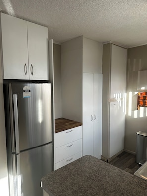 A modern kitchen with white cabinets, a stainless steel refrigerator, and a granite countertop.