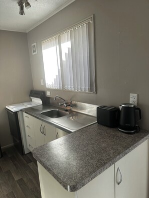 A kitchen with a granite countertop, stainless steel sink, and a black coffee maker.