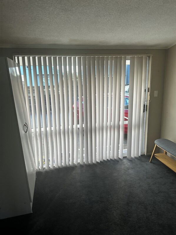 A room with a sliding door leading to an outdoor area, a bench, and a carpeted floor.