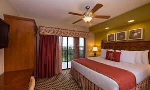 A hotel room with a bed, a ceiling fan, a window with curtains, a wall-mounted TV, and a balcony. - AWESOME STUDIO @ Westgate Lakes Resort & Spa (Orlando)