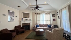 A living room with a fireplace, ceiling fan, and a sofa.