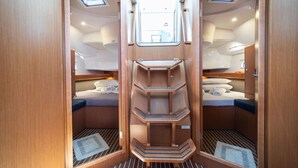 Een compact, goed verlicht interieur met een centraal wandrek, twee bedden met hoofdborden en dakramen.