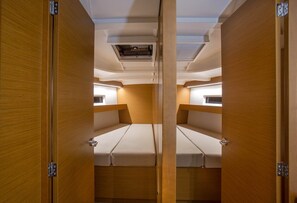 Une cabine compacte équipée de deux lits, d’un appareil de climatisation fixé au plafond et de lambris en bois.