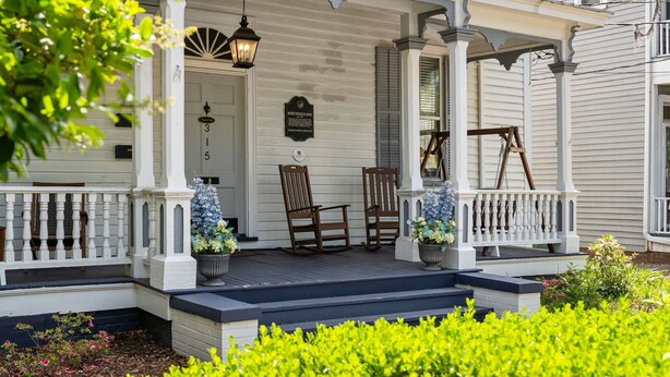 A porch with two rocking chairs, a potted plant, and a plaque. - Historic Wilmington Estate, 5BR/3 Suites - Riverwalk, VIP Parking (Wilmington)