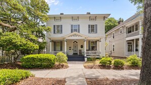 A two-story house with a front porch, a central entrance, and a small front yard with shrubs. - Historic Wilmington Estate, 5BR/3 Suites - Riverwalk, VIP Parking (Wilmington)