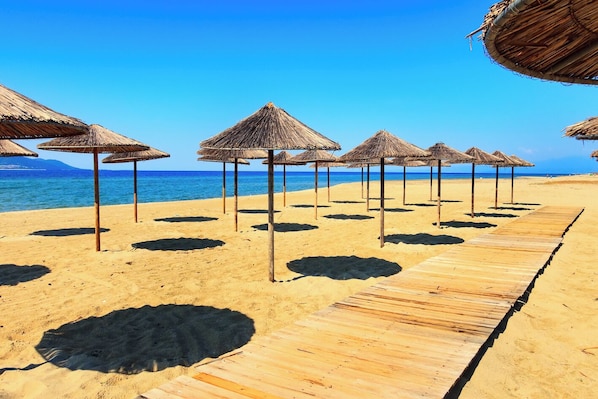 Ein Strand mit Holzstegen und Reetdachschirmen.