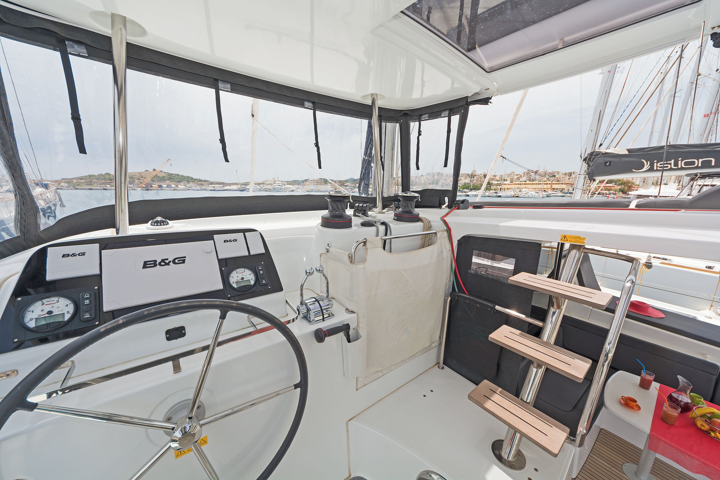 A boat's helm station with B&G navigation equipment, a headrest, and a view of the marina.