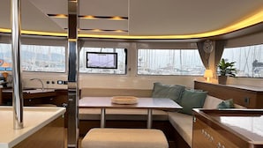 A compact interior with a dining area, a small table, and a bench. - Sun-Kissed Sailing Adventure in Islas Sarónicas (Alimos)