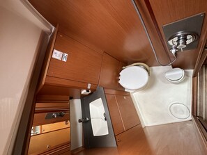 Ein kleines Badezimmer mit Toilette, Waschbecken und Duschbereich.