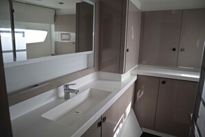 A modern bathroom with a large mirror, a sink, and cabinets. - Sun-Kissed Sailing Adventure in Islas Sarónicas (Alimos)