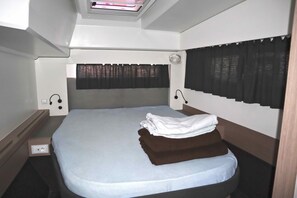 A single bed with a white mattress, a brown blanket, and a headboard with a curtain. - Sun-Kissed Sailing Adventure in Islas Sarónicas (Alimos)