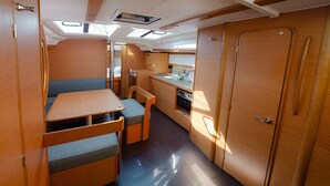 A compact kitchen with a dining area, a small table, and a bench. - Sun-Kissed Sailing Adventure in Islas Esporadas (Skiathos)