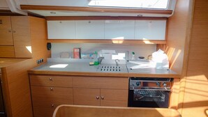 A compact galley with a sink, stove, and storage cabinets. - Sun-Kissed Sailing Adventure in Islas Esporadas (Skiathos)