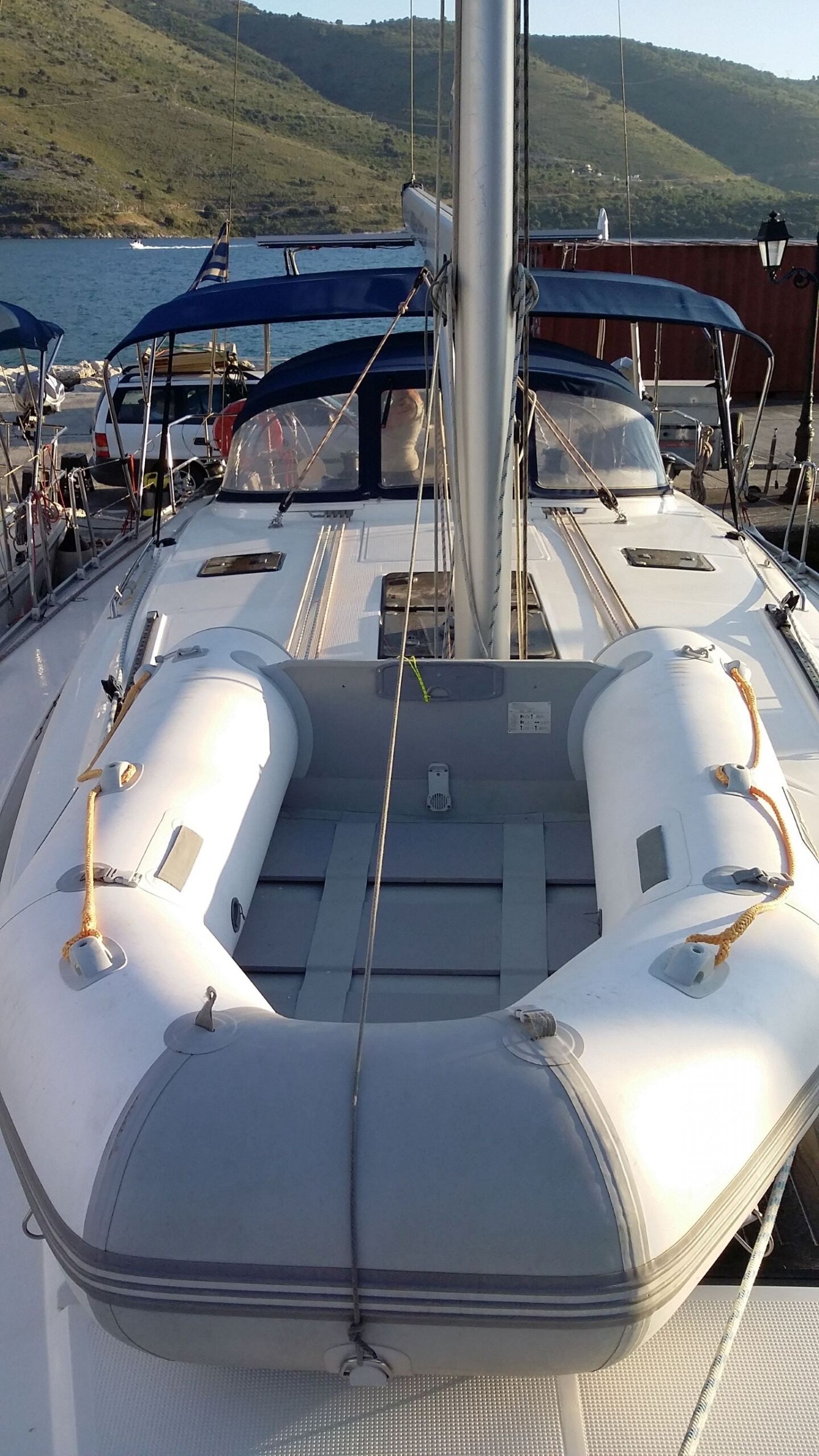 A boat's deck with a central seating area, a mast, and a view of the water and hills in the background.