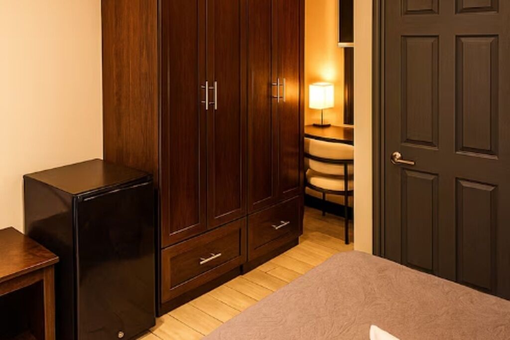 Een slaapkamer met een bed, een kast, een bureau, een stoel en een lamp.