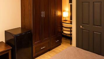 Een slaapkamer met een bed, een kast, een bureau, een stoel en een lamp.