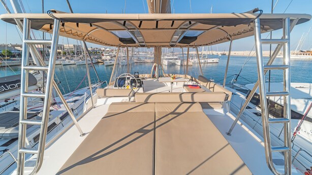 A boat deck with a cushioned seating area, a steering wheel, and a table.