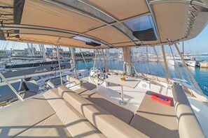 A yacht deck with seating, a steering wheel, and a view of the marina.