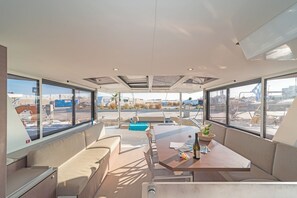 Ein modernes Interieur mit einem langen Tisch, Sitzgelegenheiten und großen Fenstern mit Blick auf ein Flughafengelände.