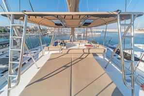 Ein Bootsdeck mit einer gepolsterten Sitzgruppe, einem Steuer und einem Tisch.