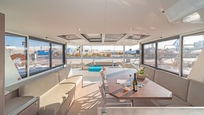 A modern interior with a long table, seating, and large windows offering views of an airport.