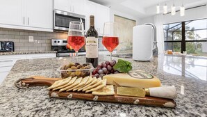 Eine Küchenarbeitsplatte mit Käse, Trauben, Oliven, Crackern und zwei Weingläsern sowie Flaschen.
