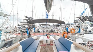 Cubierta de barco con asientos, una mesa y diverso equipo náutico.