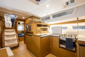 A compact kitchen with a stove, sink, and storage cabinets. - Sun-Kissed Sailing Adventure in Islas Sarónicas (Alimos)