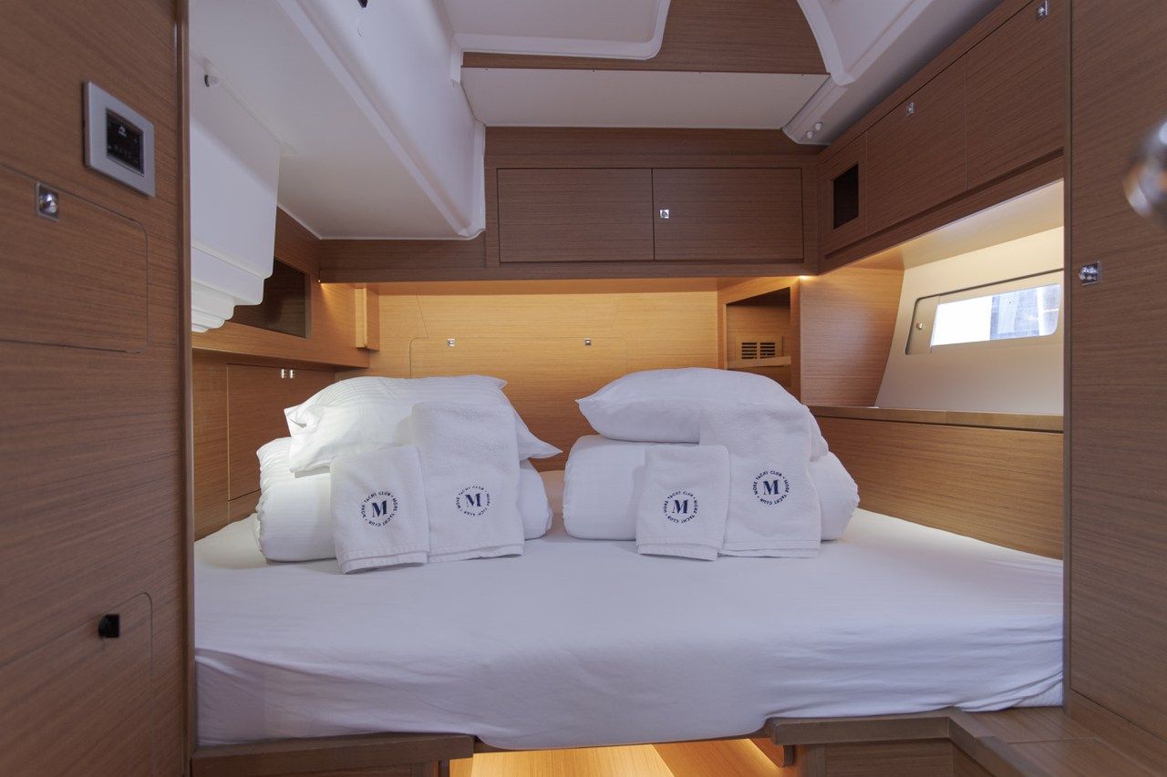 A compact, well-lit cabin with a bunk bed, wooden paneling, and a small window.
