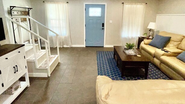 A living room with a sofa, coffee table, and a staircase leading to another room. - Adorable 1-bedroom barn in Mineola, East Texas also known as Lake Country (Mineola)