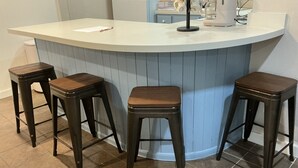 A kitchen with a curved island, three wooden bar stools, and a coffee maker. - Adorable 1-bedroom barn in Mineola, East Texas also known as Lake Country (Mineola)