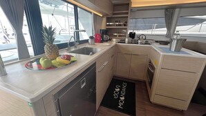 Una cocina compacta con lavavajillas, un fregadero y una estufa. Hay un frutero en la encimera y un felpudo negro con la palabra 'MOUNTAIN'.