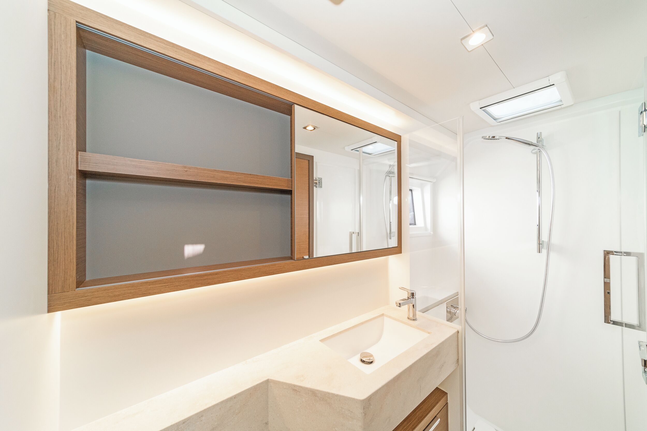 Un baño con un espejo grande, un lavamanos y una ducha.