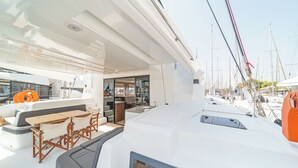 Cubierta de un yate con zona de estar, una pequeña cocina y vista al puerto deportivo.