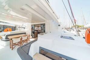 Das Deck einer Yacht mit einer Sitzecke, einer kleinen Küche und Blick auf den Hafen.