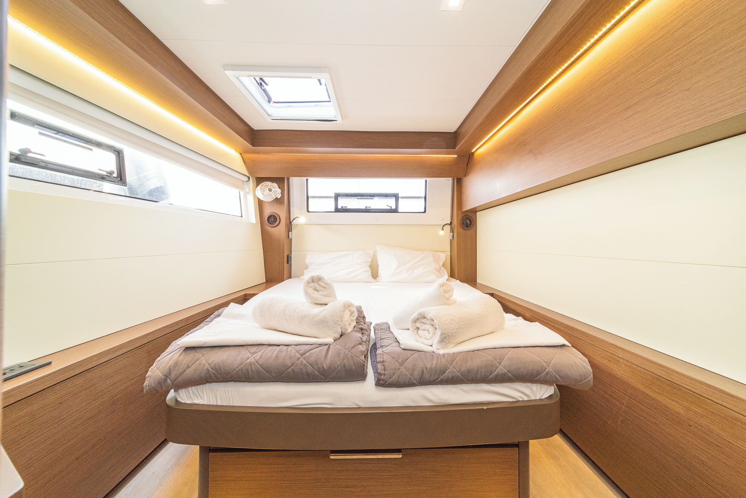 Ein kleines, helles Schlafzimmer mit Bett, Kissen und einem Oberlicht.