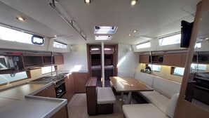 A compact kitchen with a central island, a dining area with a bench, and a small seating space. - Sun-Kissed Sailing Adventure in the Saronic Islands (Laurium)