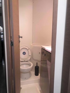 A small, compact bathroom with a toilet, bidet, and a toilet paper holder. - Sun-Kissed Sailing Adventure in the Ionian Islands, Lefkada (Lefkada)