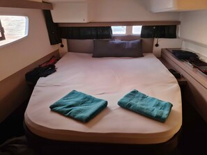 A compact bed with a headboard, a pillow, and two folded towels. - Sun-Kissed Sailing Adventure in the Ionian Islands, Lefkada (Lefkada)